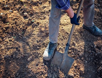 L'homme creusant la terre avec une bêche dans une vue à angle bas de ses jambes dans un concept de jardinage et d'horticulture