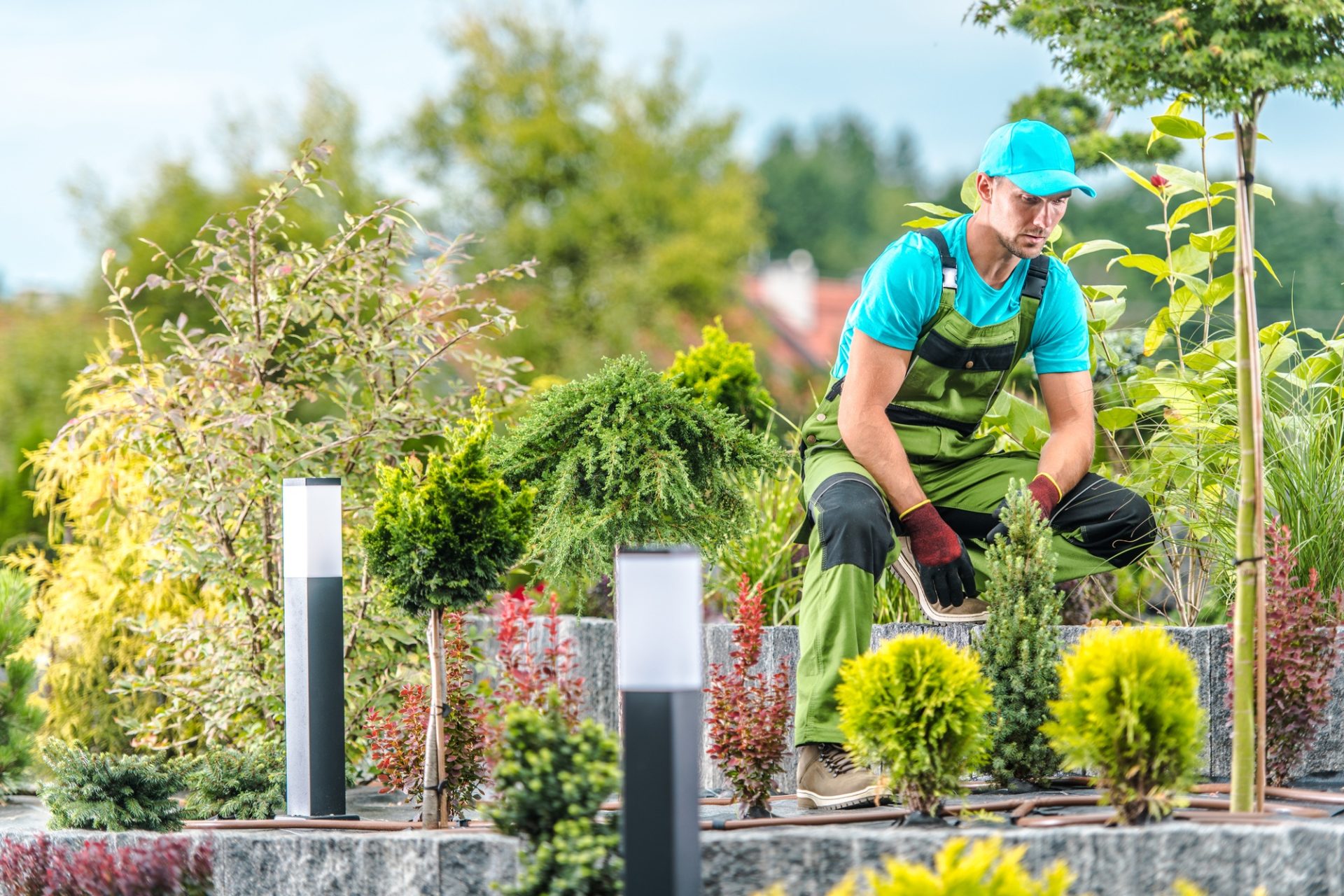 Le jardinier masculin de l'âge moyen de race blanche prenant un moment de repos pendant l'aménagement paysager un grand lit d'île dans le jardin de l'arrière-cour de son client.